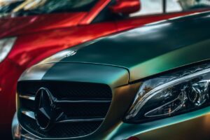 Detailed view of a luxury Mercedes Benz with focus on the emblem and headlight.